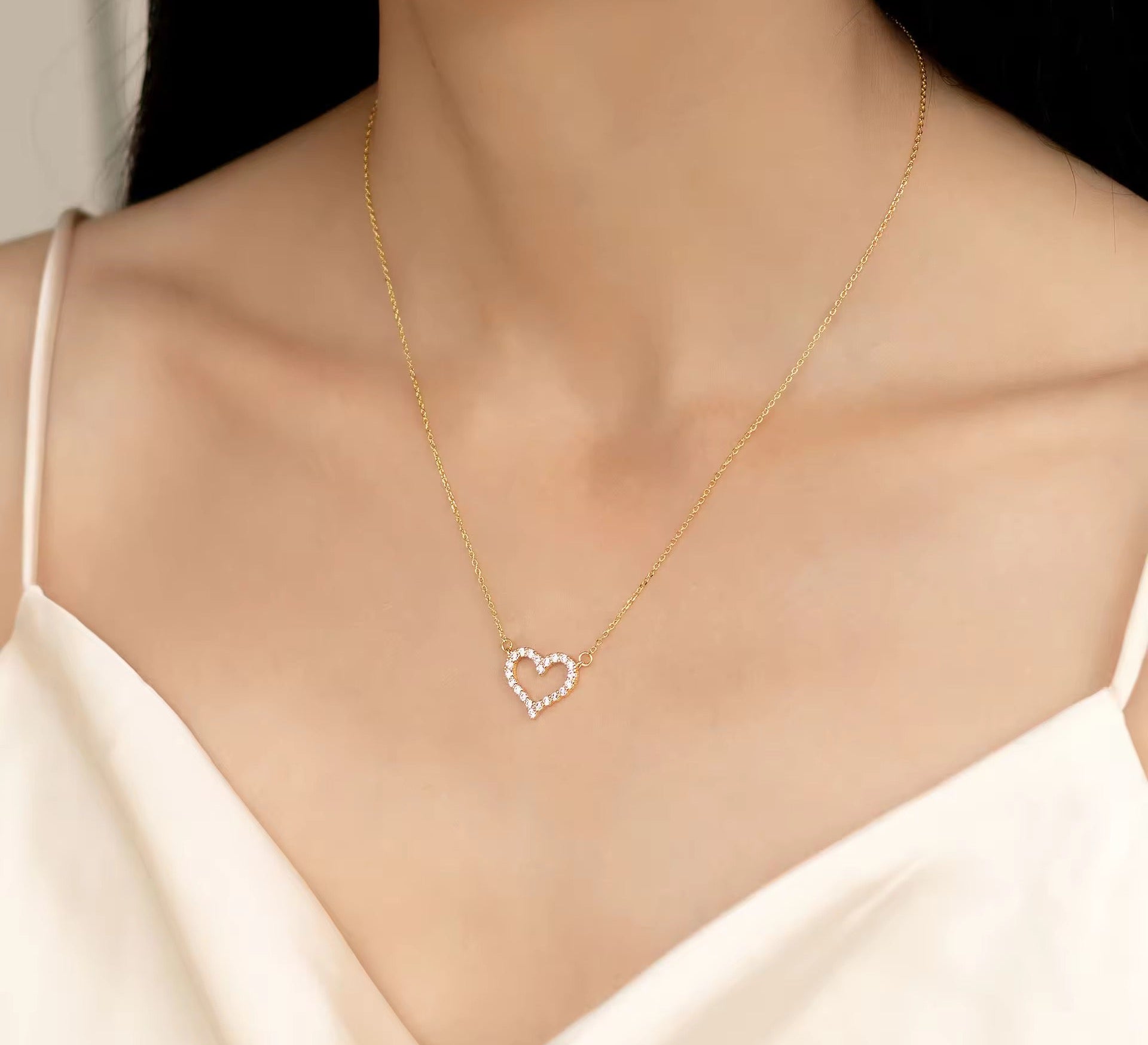 Gold heart-shaped necklace on a mannequin with a white top