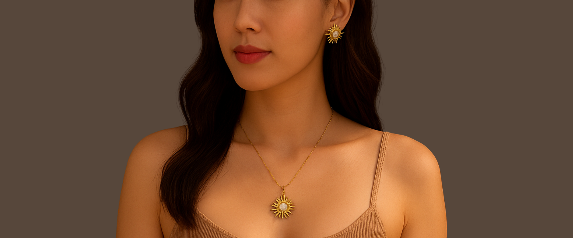 Woman wearing a gold necklace and earrings against a brown background